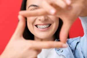 Beautiful woman with dental braces on red background