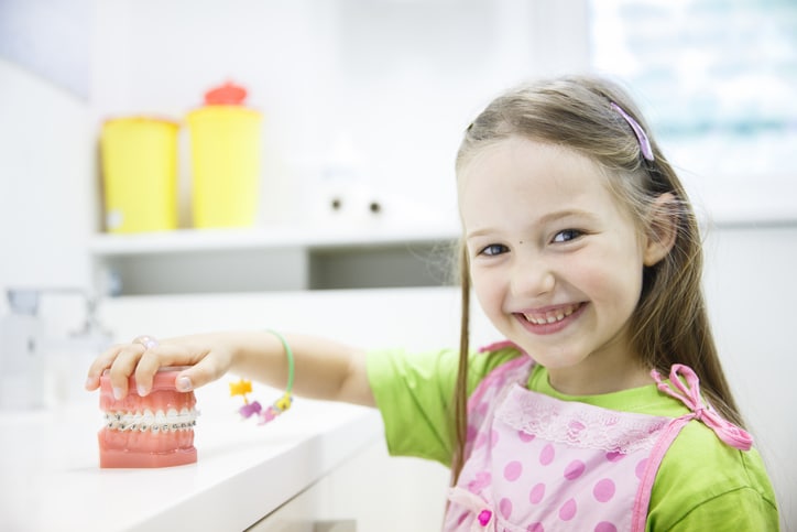 Girl touching model teeth with braces