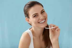 Smiling woman with healthy teeth using removable clear braces aligner